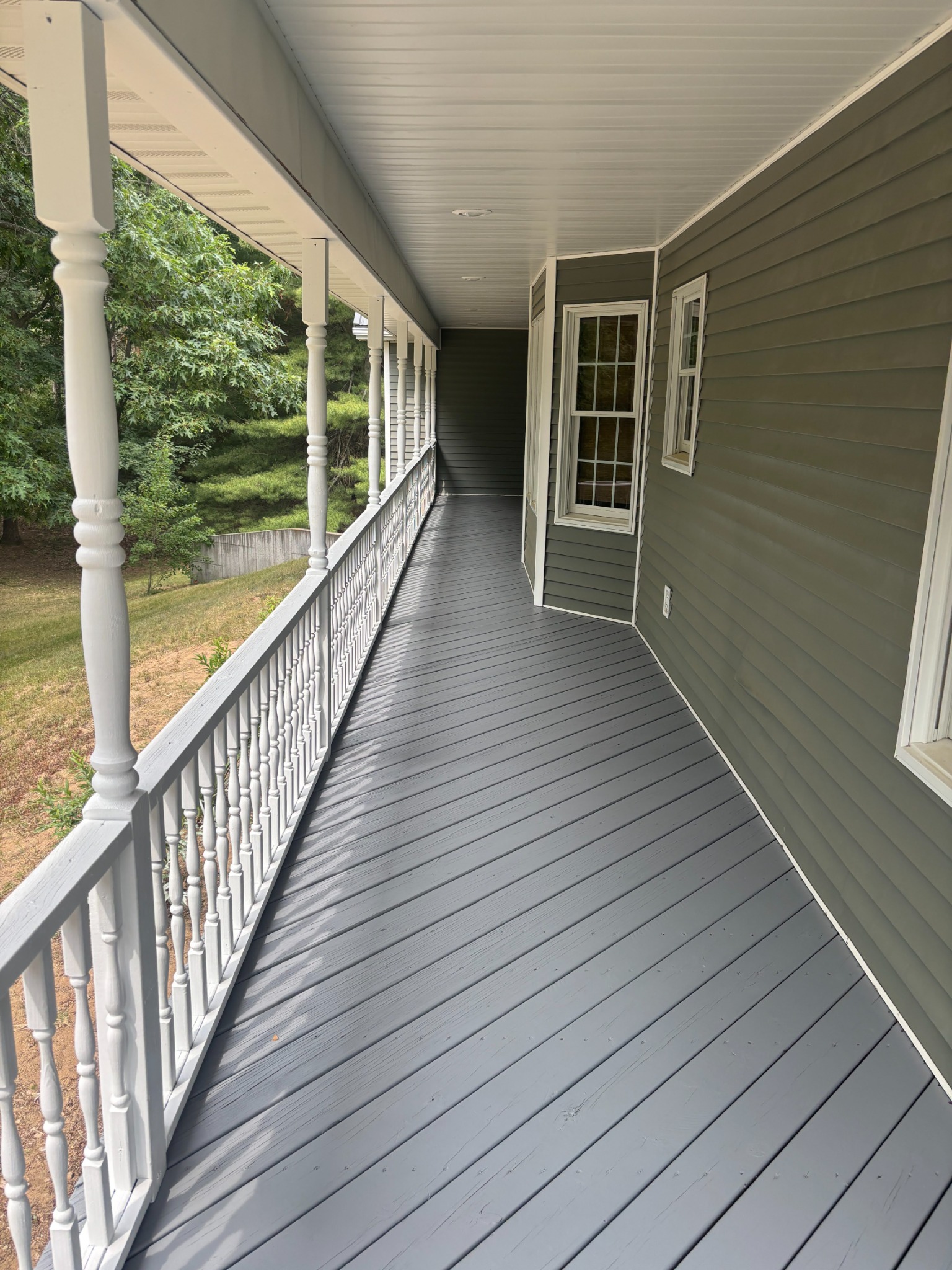 Finished covered porch with charcoal deck boards and white railings