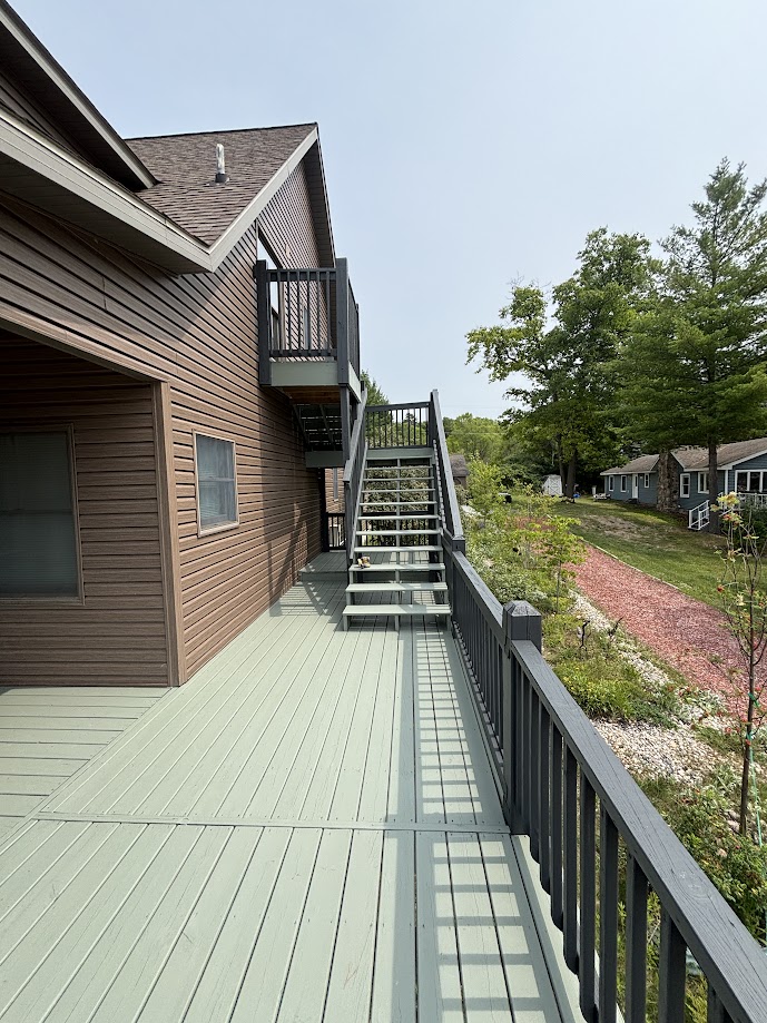 Finished sage green deck and dark railings beside a home